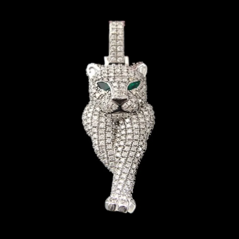 A silver and diamond-encrusted jewelry piece in the shape of a walking jaguar with green gemstone eyes and a vertical charm or pendant hanging from the top of the head, set against a black background.