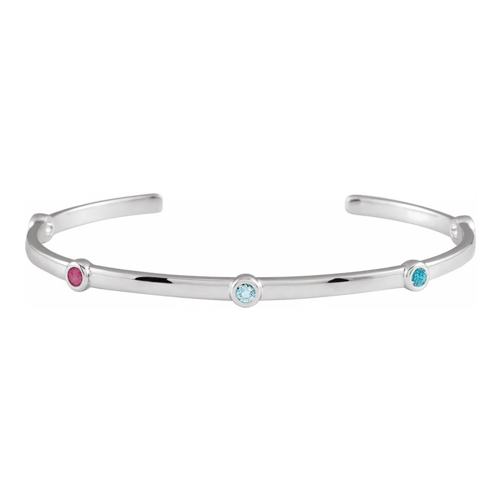 Silver bracelet with three colorful gemstones, including red, blue, and turquoise, set into it.