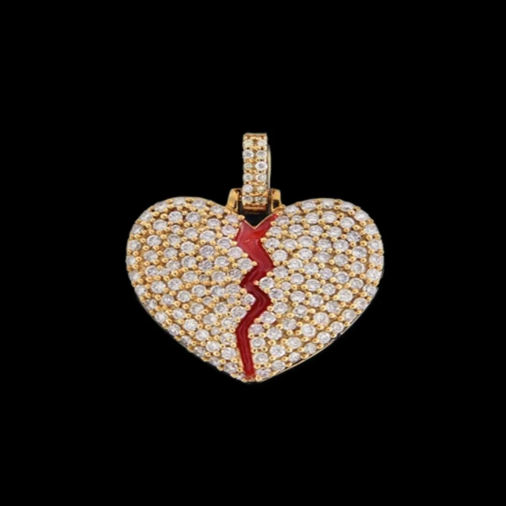 Gold heart-shaped pendant encrusted with diamonds, featuring a red crack design down the center, displayed against a black background.