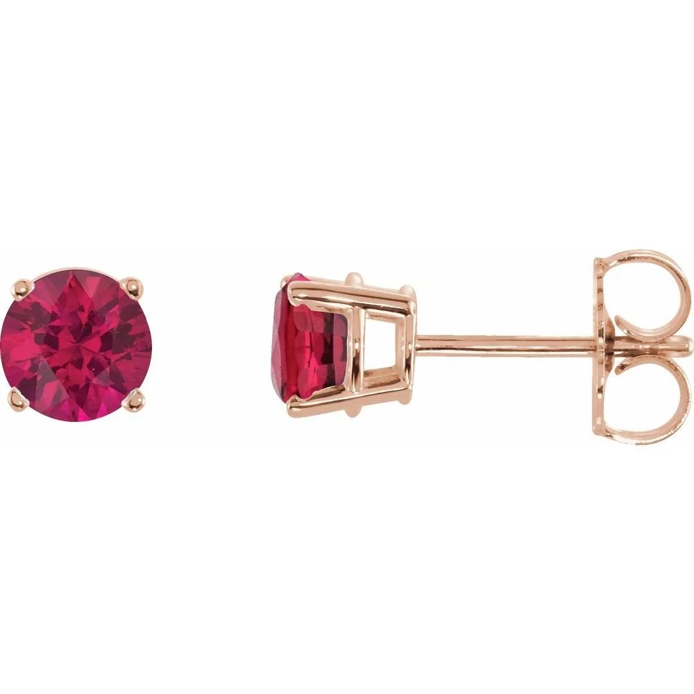 A pair of pink gemstone stud earrings with a round cut, set in a metal prong setting.