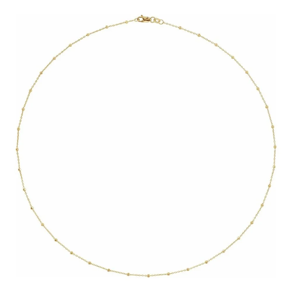 Gold necklace with small evenly spaced beads, laid flat against a white background.