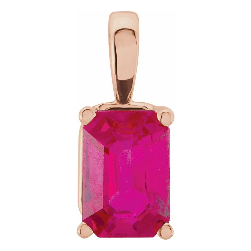 A close-up of a pendant with a large rectangular pink gemstone set in a gold or rose gold metal frame.