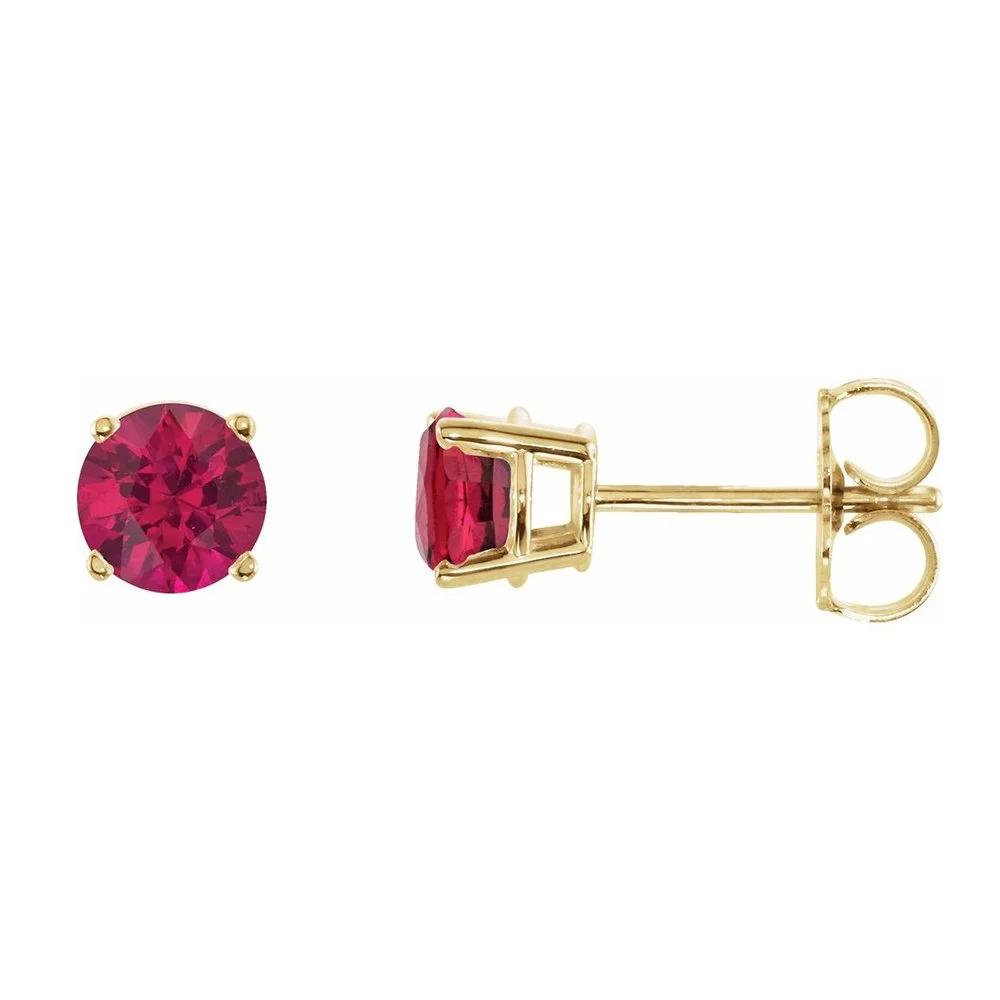 Close-up of a pair of gold stud earrings with oval-shaped red gemstones, showing the front and side view of one earring.