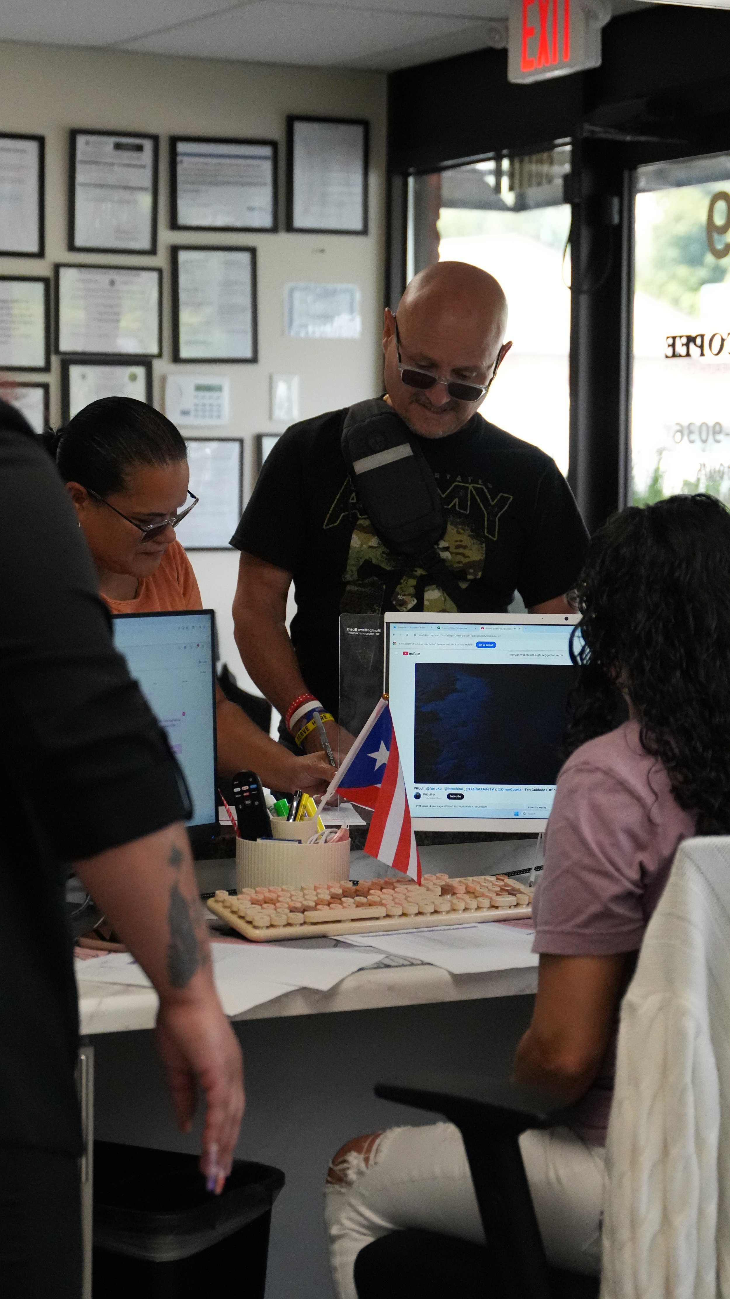 People gathered around a table with computers and a small Puerto Rican flag inside an office or conference room.