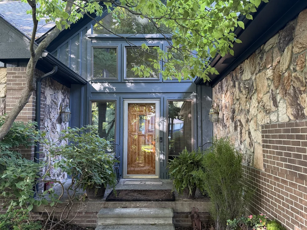 Home entry with dark blue-gray siding and a stained wood front door, painted by Levels Ahead