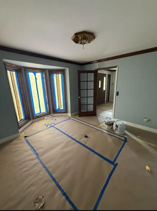 Room prepped for interior painting with floors fully covered and taped