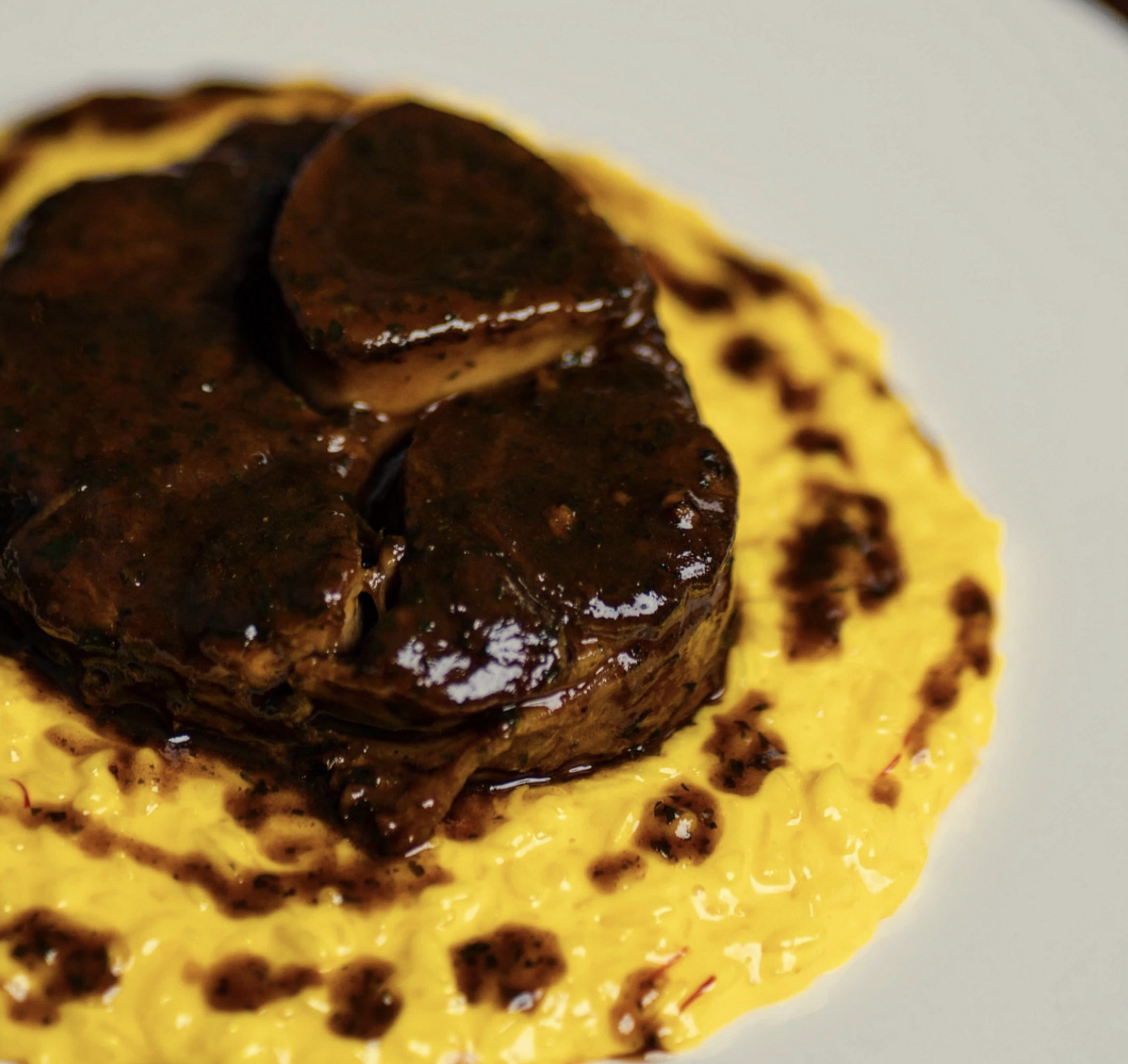 Filetto di manzo sopra una crema gialla, condito con salsa al cioccolato