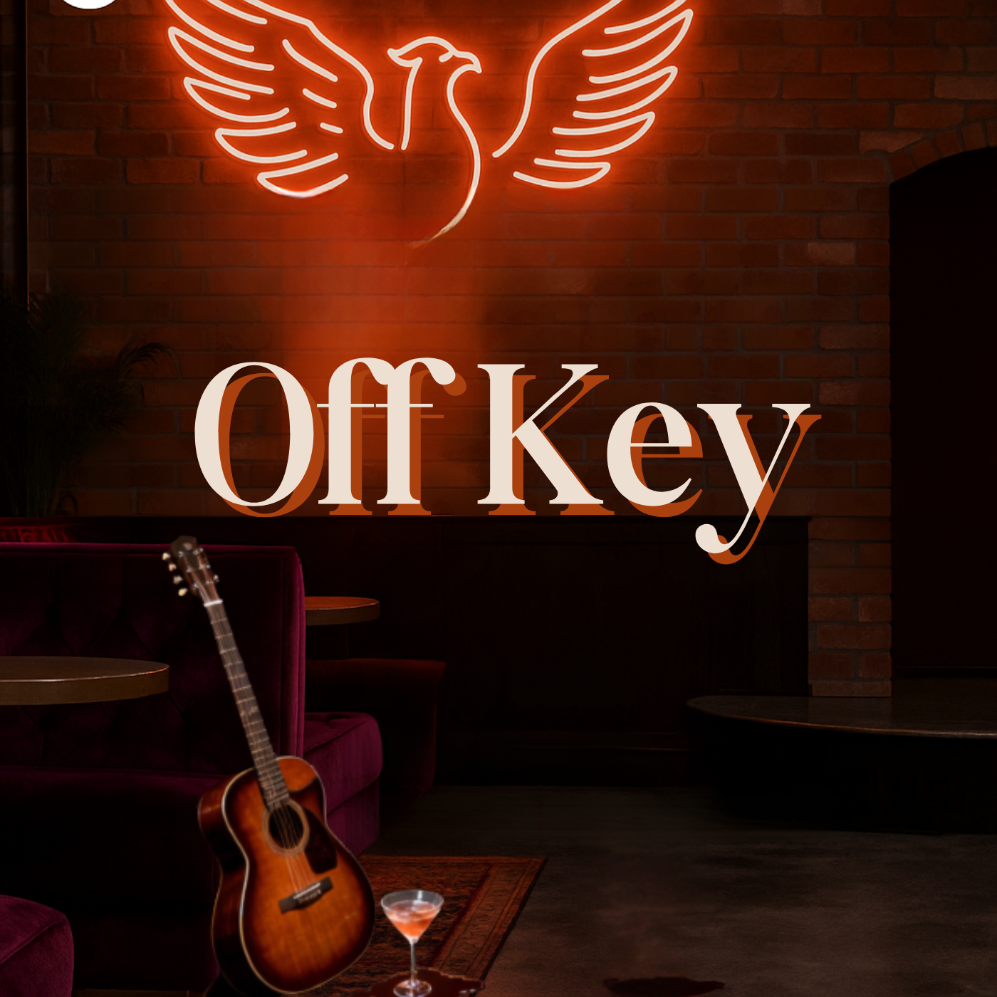 Neon sign of a bird with wings spread on a brick wall, with the words "Off Key" in front, inside a dimly lit lounge or bar featuring purple velvet chairs, a guitar, and a cocktail glass.