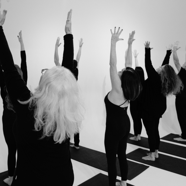 Group of women practicing yoga on mats with arms raised in a studio