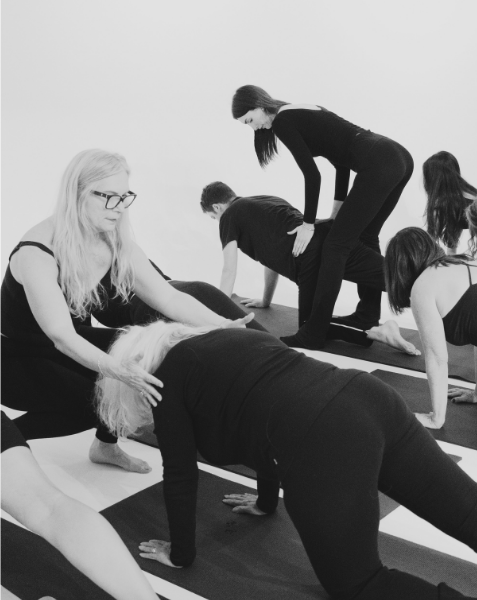 Yoga class with a group of women practicing poses on mats in a studio.