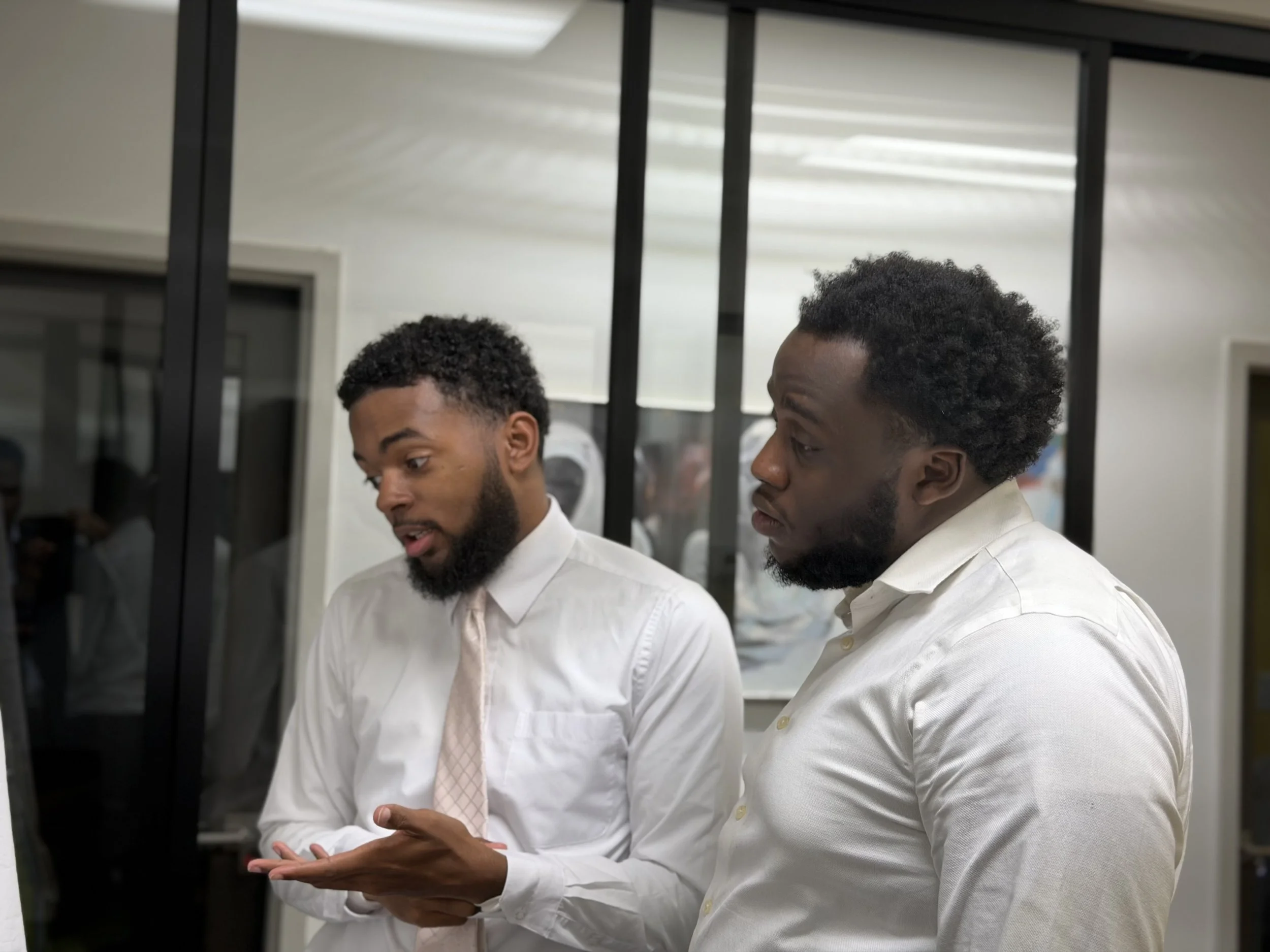 Two men in business attire having a discussion in an office setting.