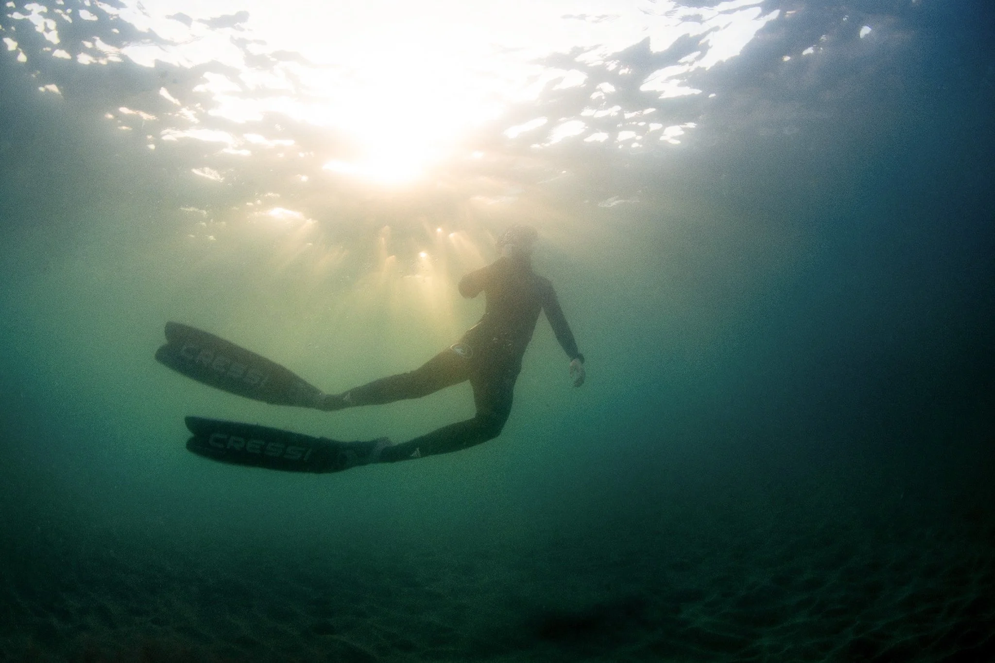 a woman in irish sea snorkelling with sun rays and in blue green water