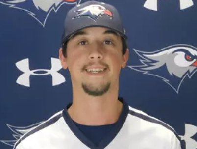 A young man smiling, wearing a baseball cap and jersey, standing in front of a backdrop with sports team logos.