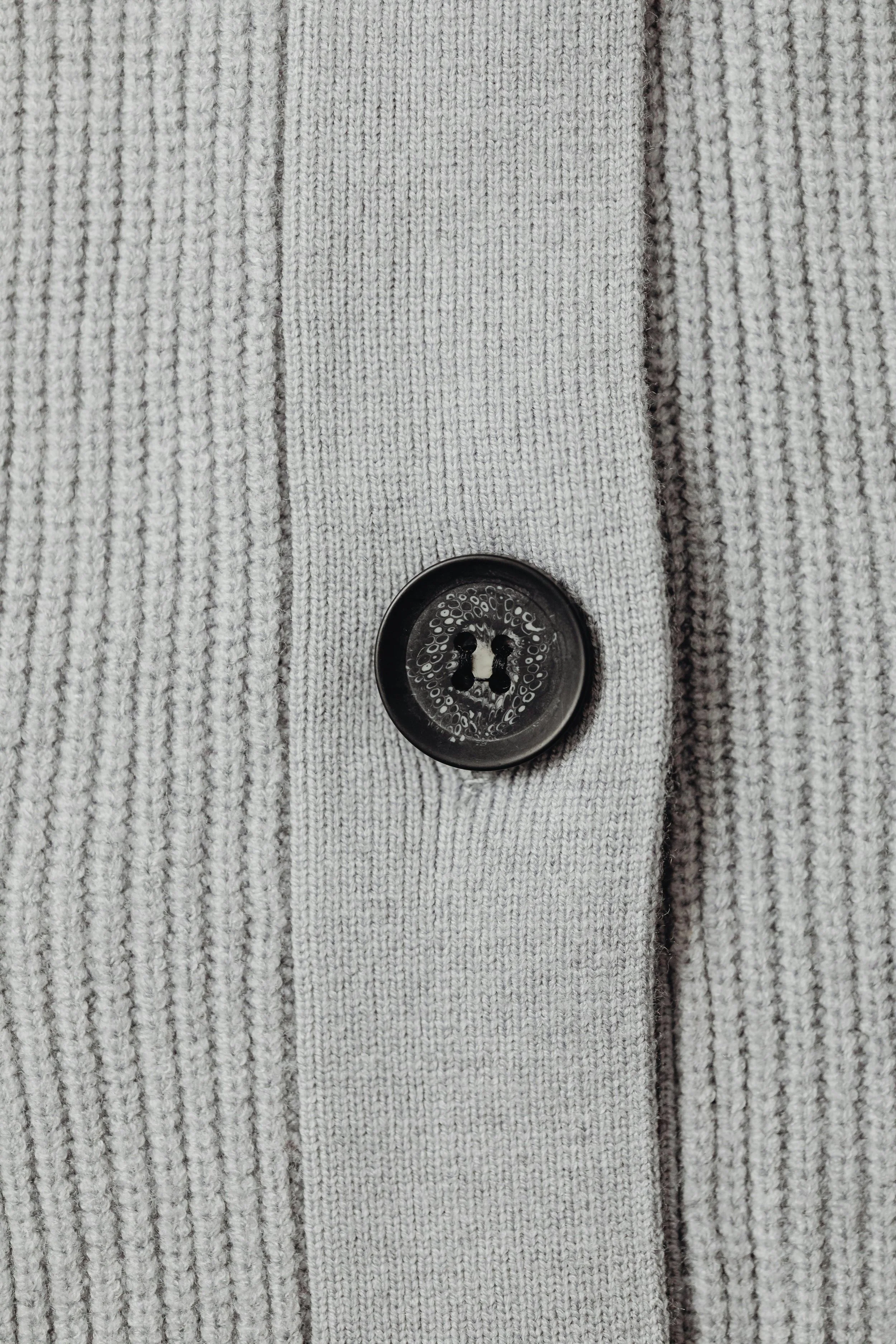 Close up of a button on a white knit cardigan