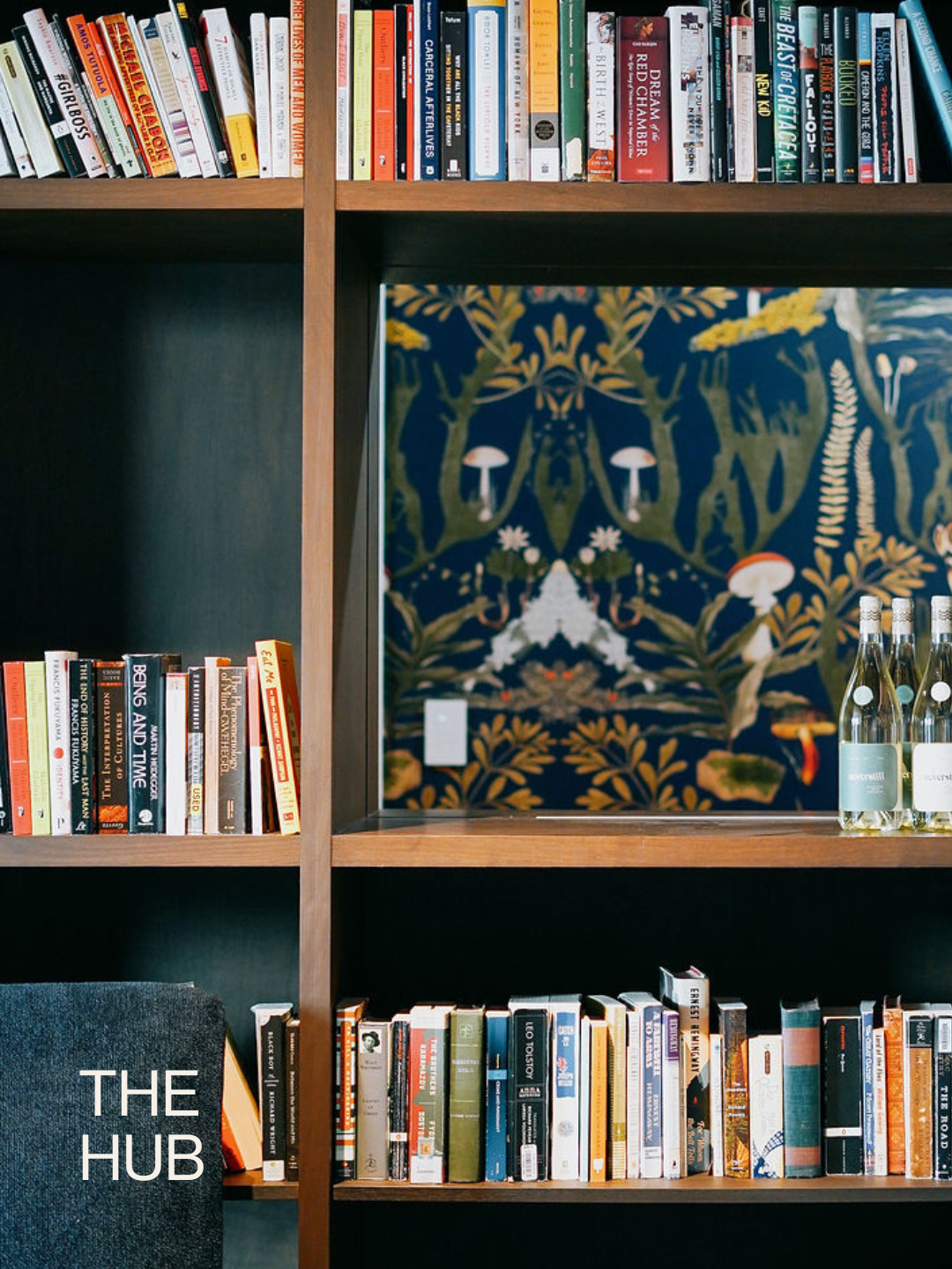 Book case full of books and speakeasy window with wine bottles