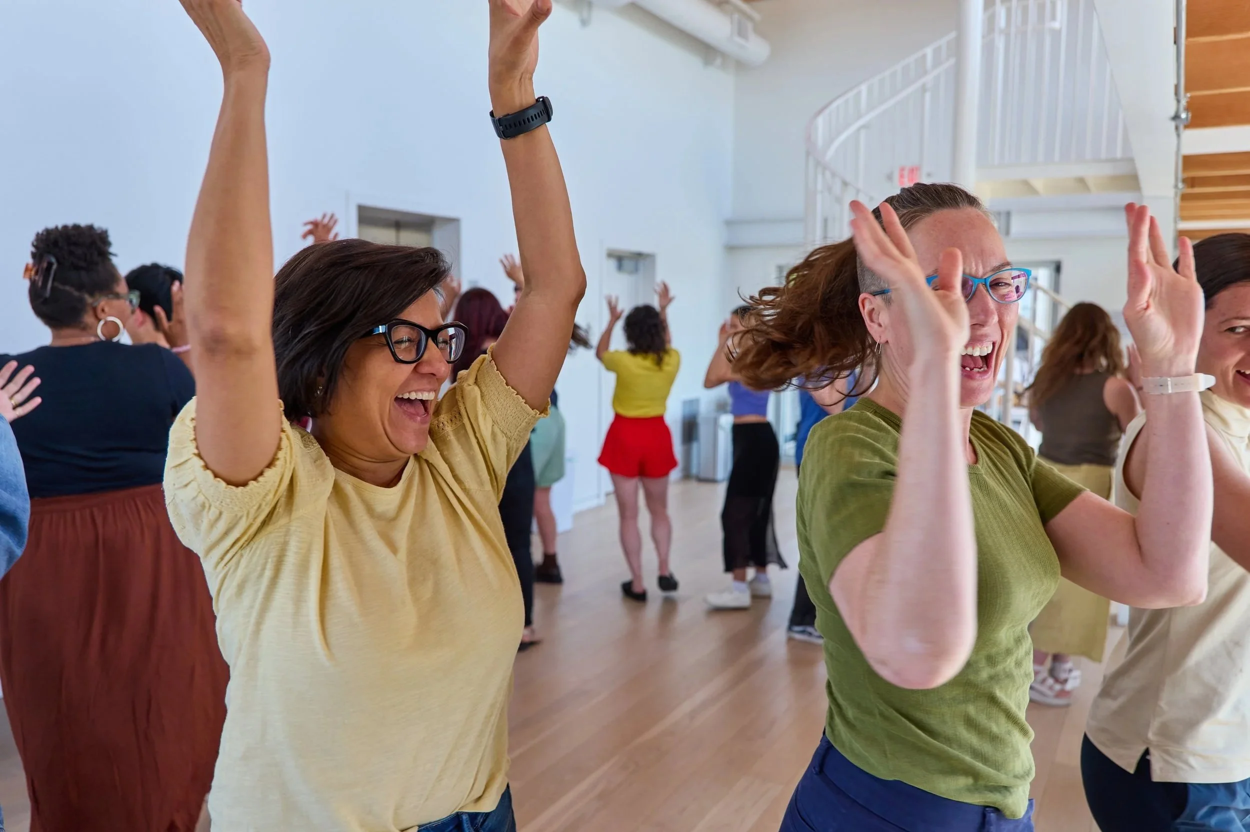 Two young women dancing with their hands up in a cirlce on the skydeck