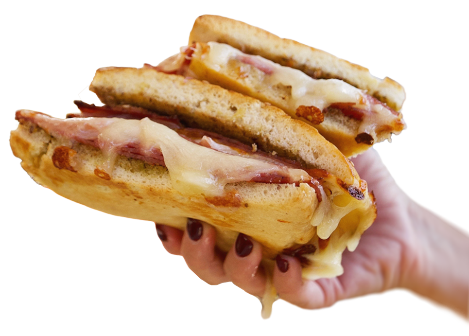 Hand holding a large grilled cheese sandwich with toasted bread, ham, and melted cheese.