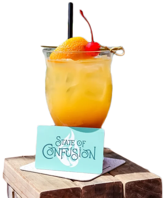 A tropical drink with an orange slice and maraschino cherry on top, served in a clear glass with a black straw, placed on a wooden surface with a 'State of Confusion' card in front.