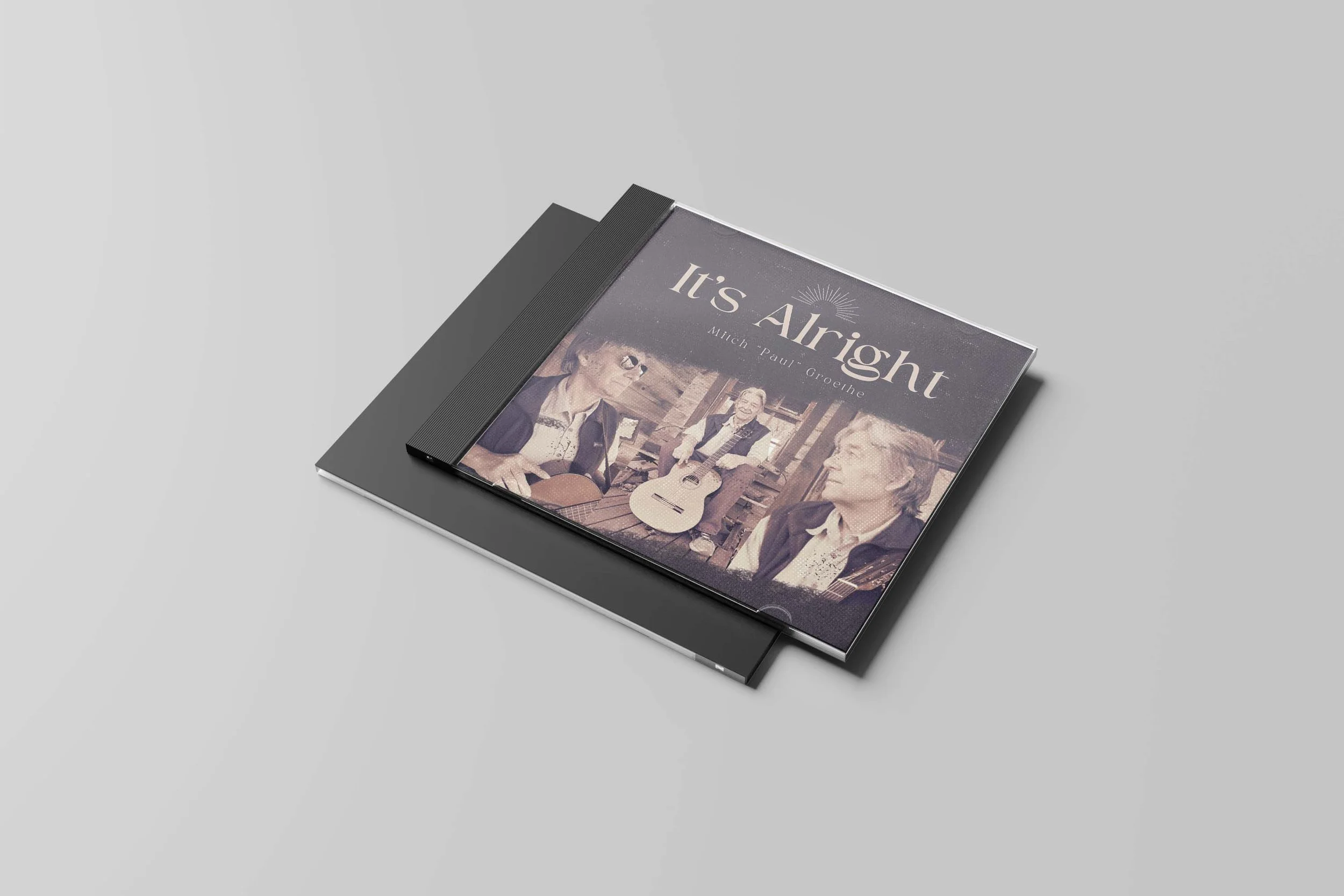 CD case titled 'It's Alright' featuring a photo of three men, two playing guitars and one standing between them, in a rustic setting.
