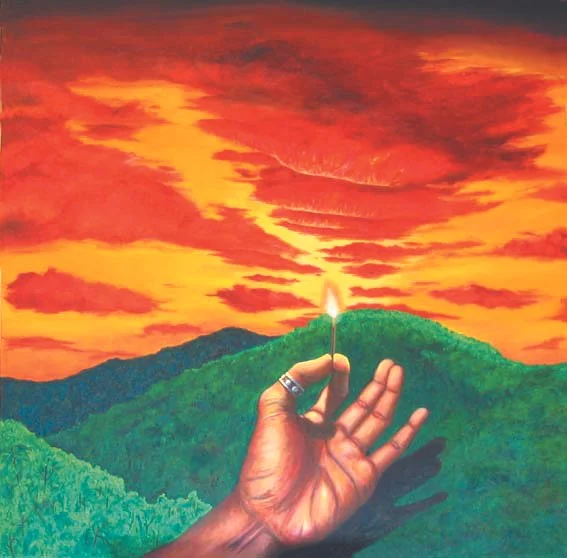 A hand holding a lit matchstick against a vibrant sunset sky over green hills.