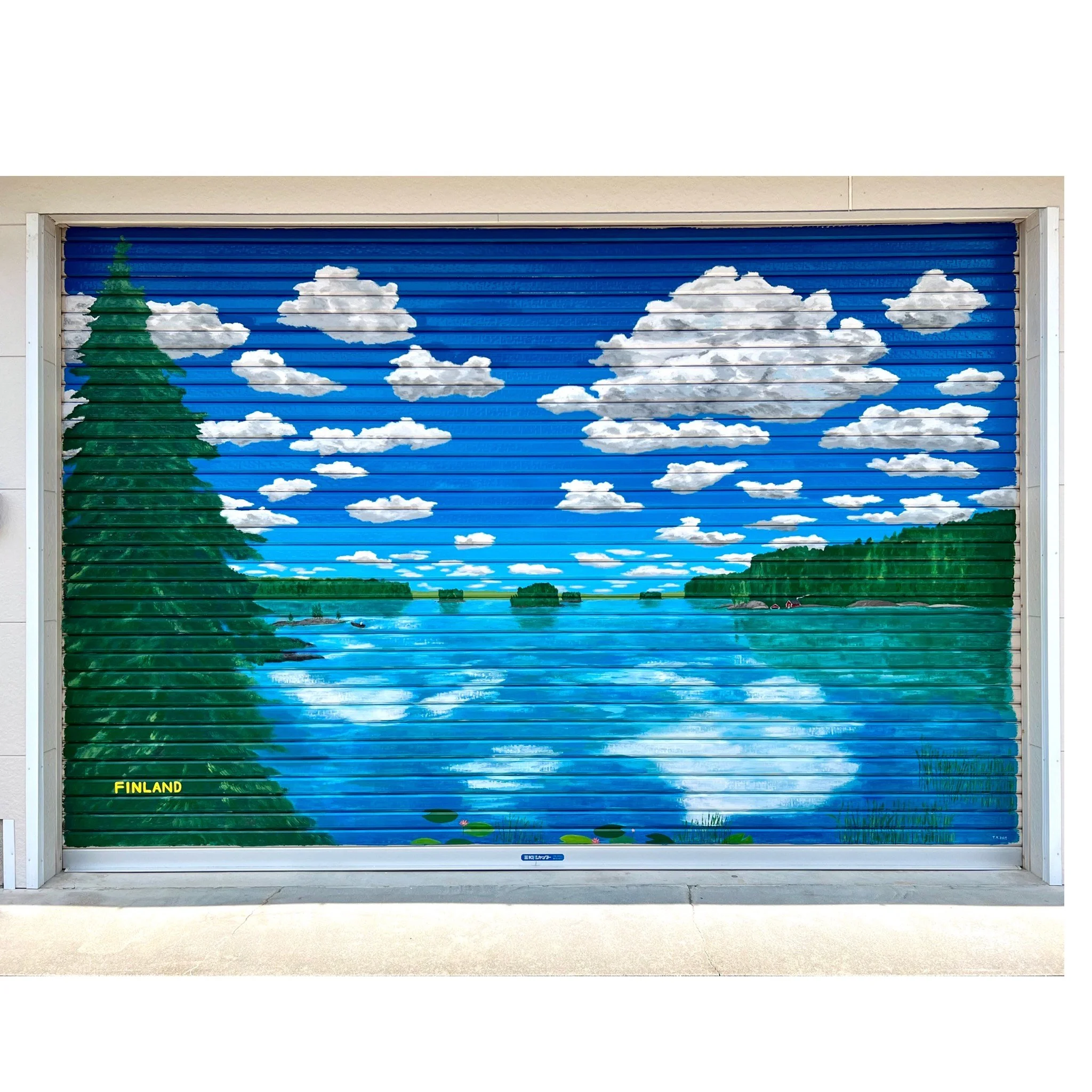 Mural of a lakeside landscape with blue skies, white clouds, a large green pine tree on the left, and a city in the distance, painted on a metal roll-up door, labeled Finland.