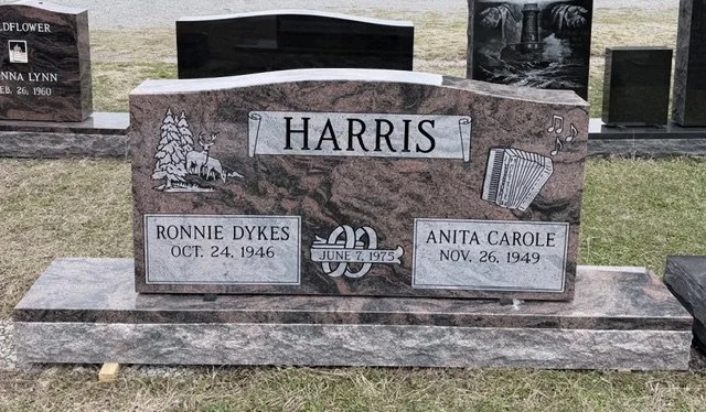 Granite headstone with the surname Harris, featuring engraved images of trees, a deer, musical notes, and an accordion, along with names and birth/death dates of Ronnie Dykes and Anita Carole.