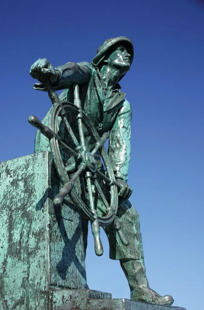 Man at the Wheel, bronze sculpture by Leonard Craske based on a painting by Augustus Buhler. In 1923, the sculpture was selected to commemorate the 300th anniversary of the first settlement of Gloucester.