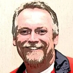 Man with light colored hair with beard and mustache wearing a red shirt with black collar