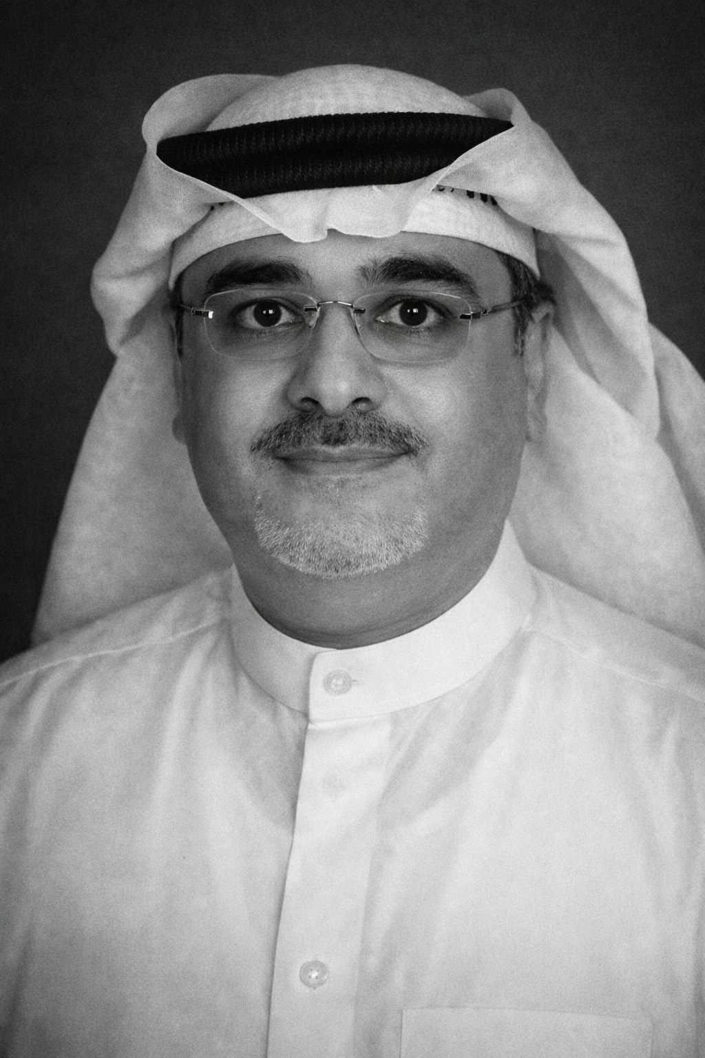 A man with glasses and a mustache wearing traditional Middle Eastern attire and a head covering, looking straight at the camera.