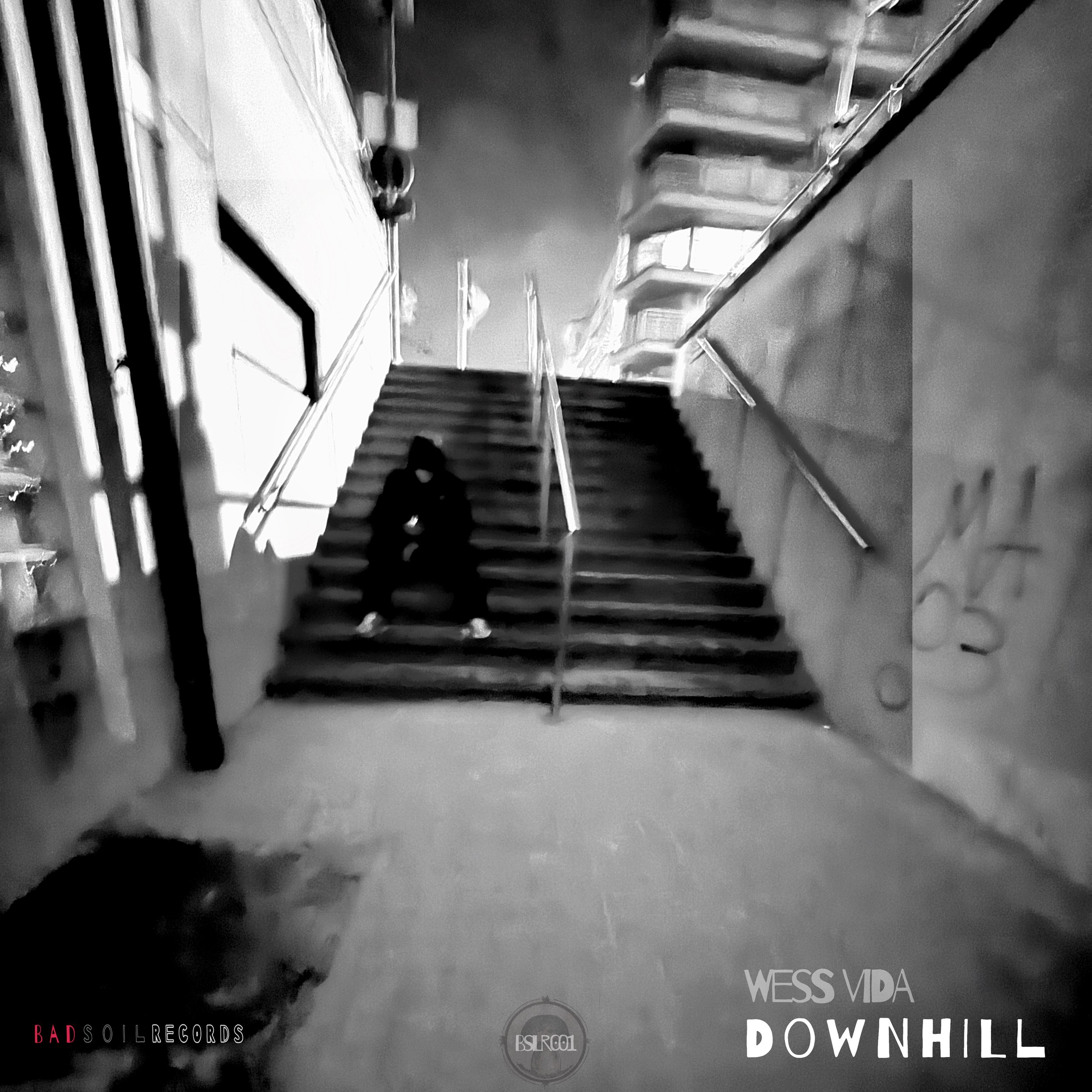 A person sitting on stairs outside a building at night, with city lights and structures in the background.
