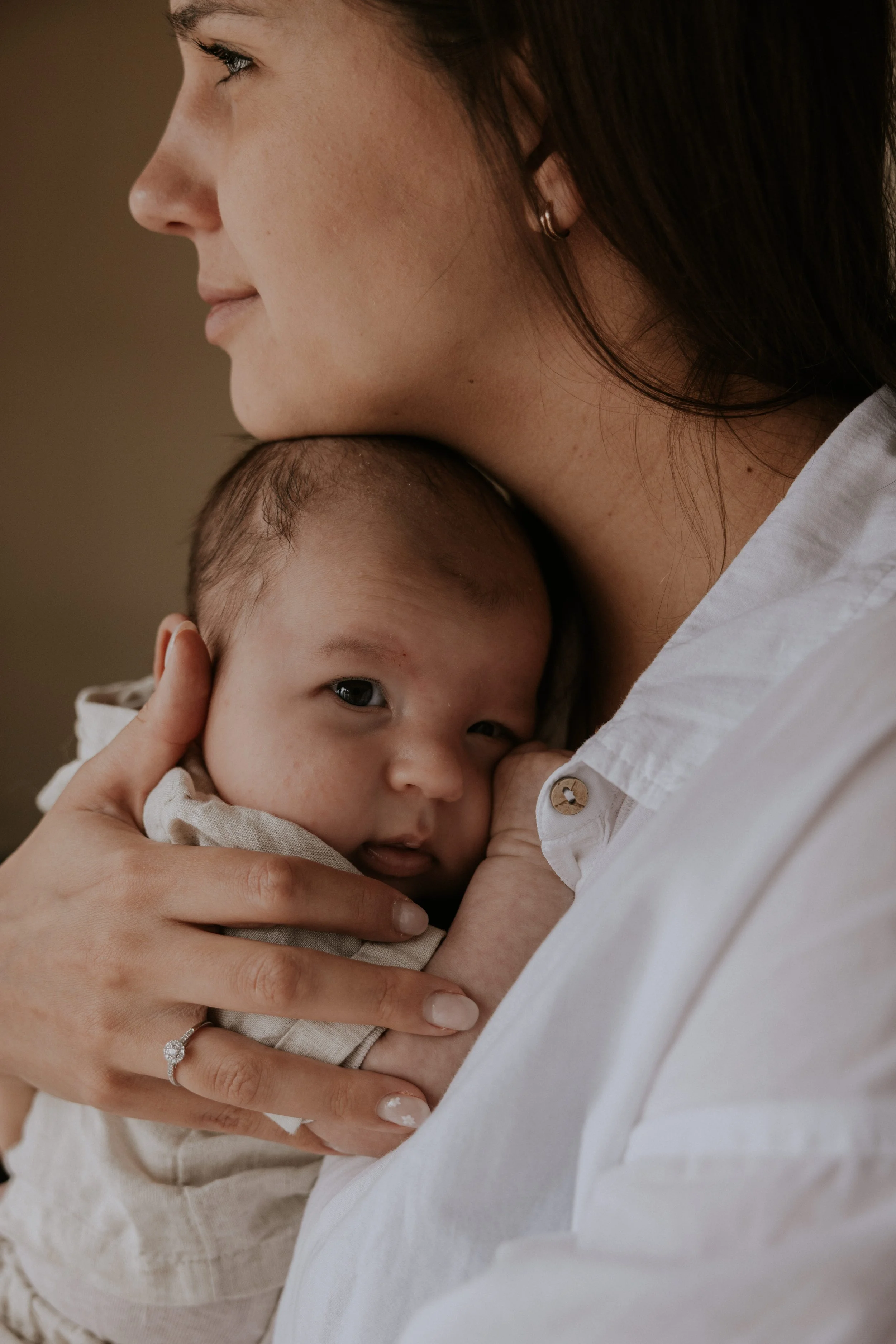 Close-up van een vrouw die haar baby vasthoudt en tegen haar borst houdt, met een zachte uitdrukking.