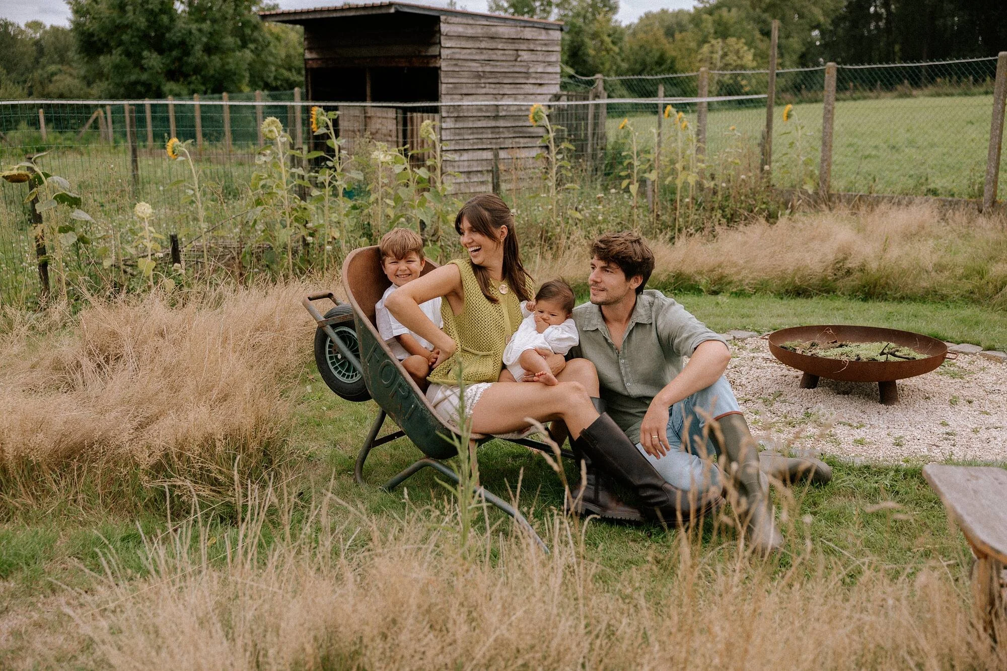 Een familie zit samen in een tuin, lachend en genietend van het buitenleven.