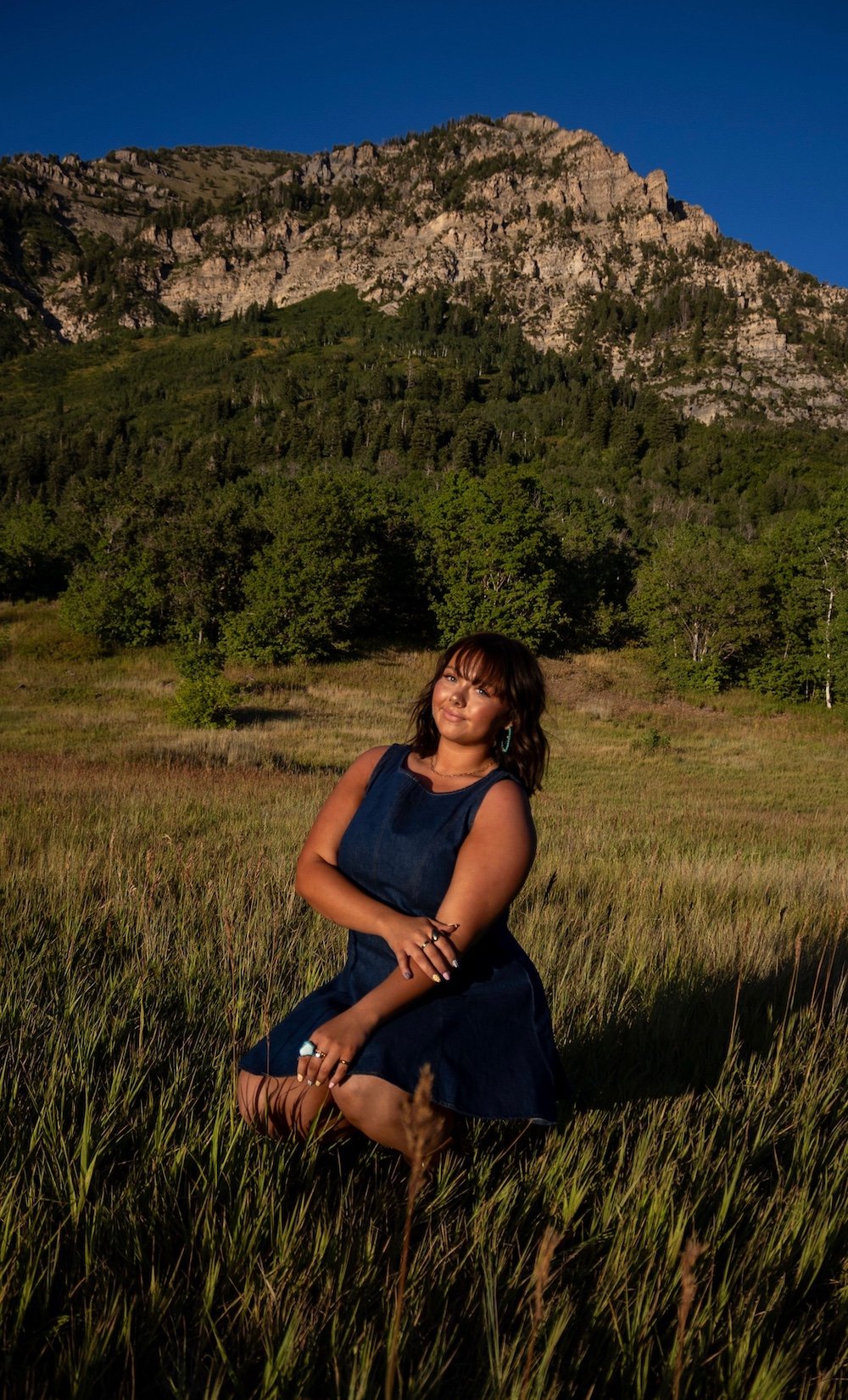 tanned girl sitting in front of a mountain