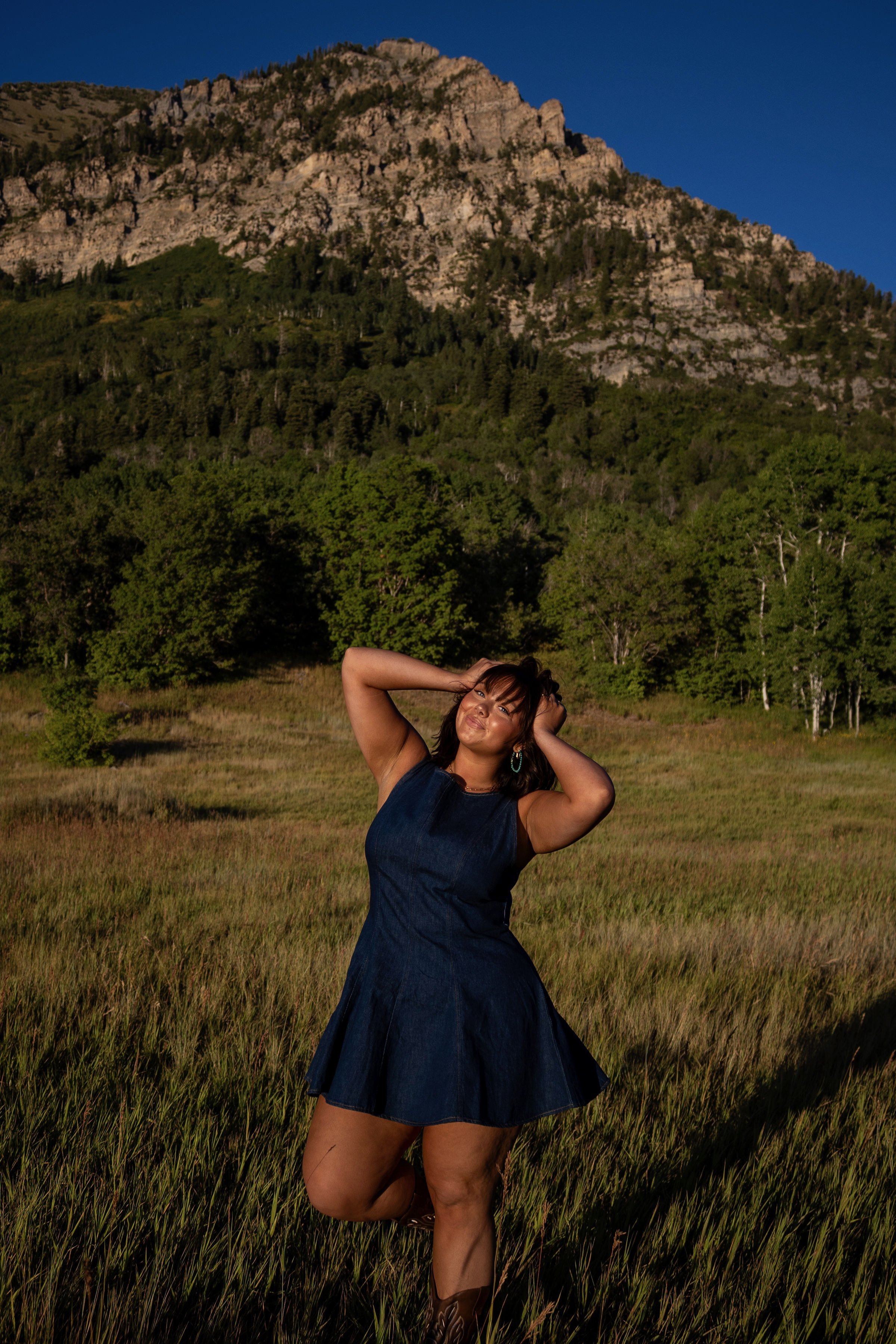 Woman pulling her hair back while standing in front of a mountain