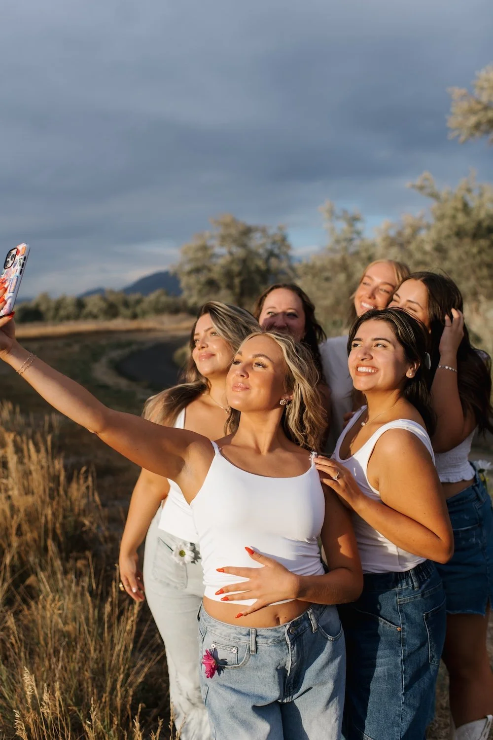 A group of girls with fresh, airbrush spray tans smiling as they take a selfie