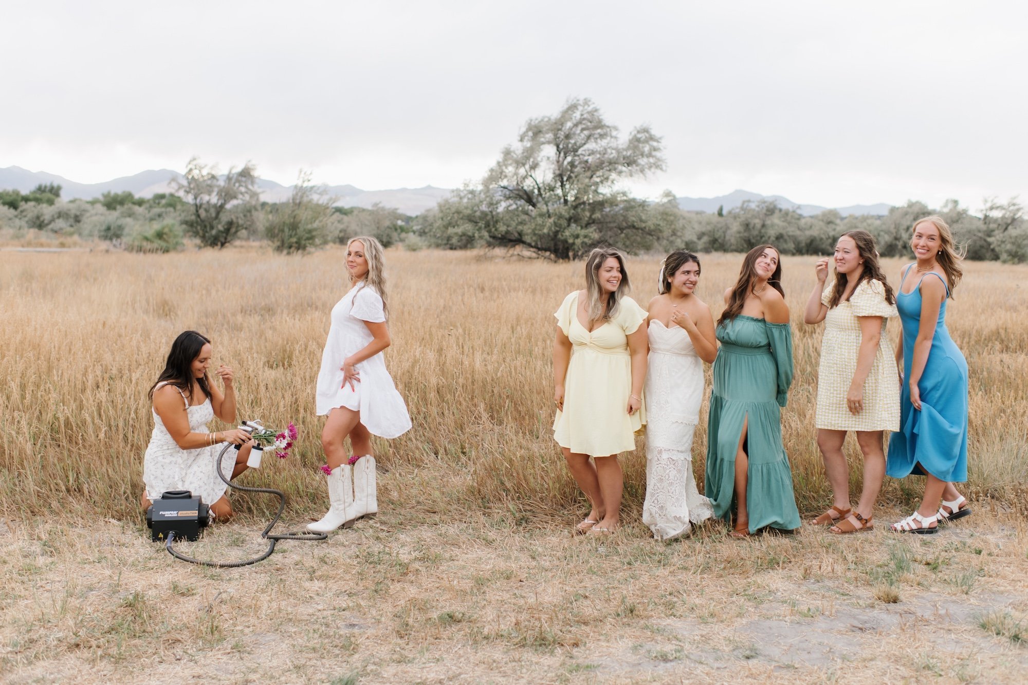 Airbrush spray tanning artist spraying women in a field