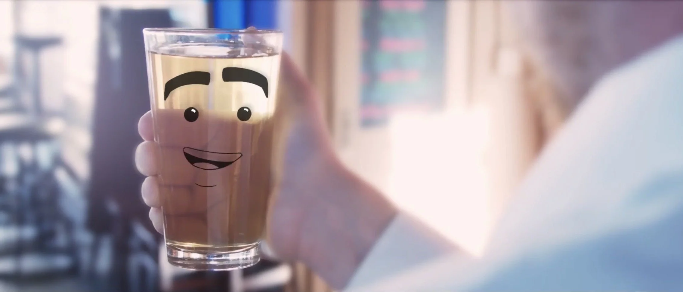 A hand holding a pint of beer with a cartoon face, including eyes, eyebrows, and a smiling mouth with a tongue visible.