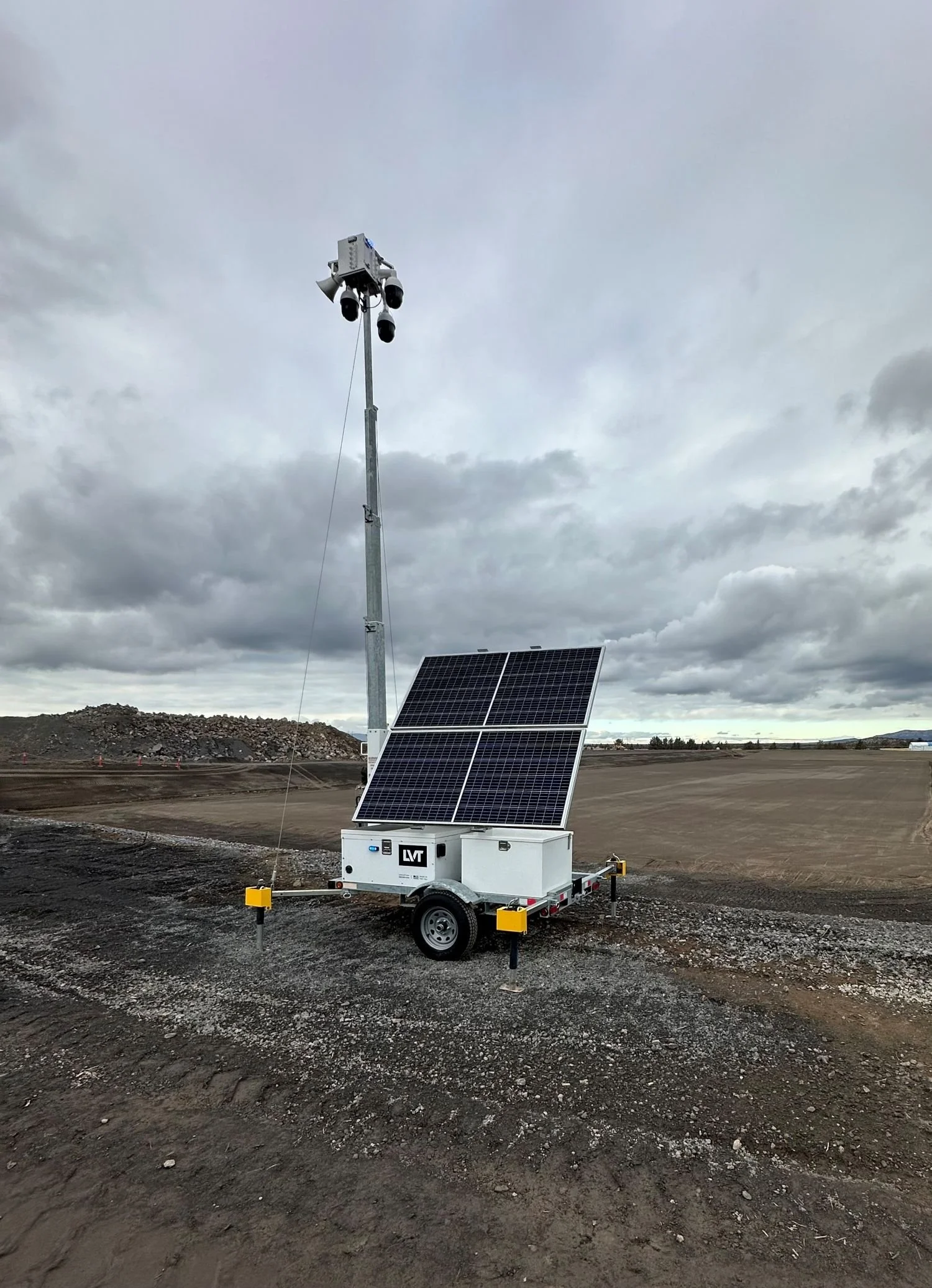 Portable solar-powered weather station with solar panels and cameras on a cloudy, open landscape.