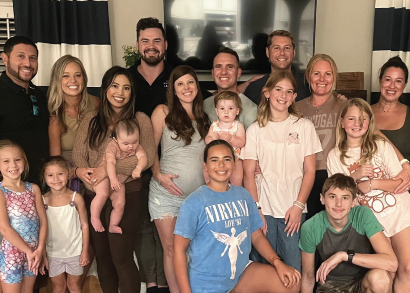 A group of people, including children and adults, gathered together indoors for a photo, smiling at the camera.