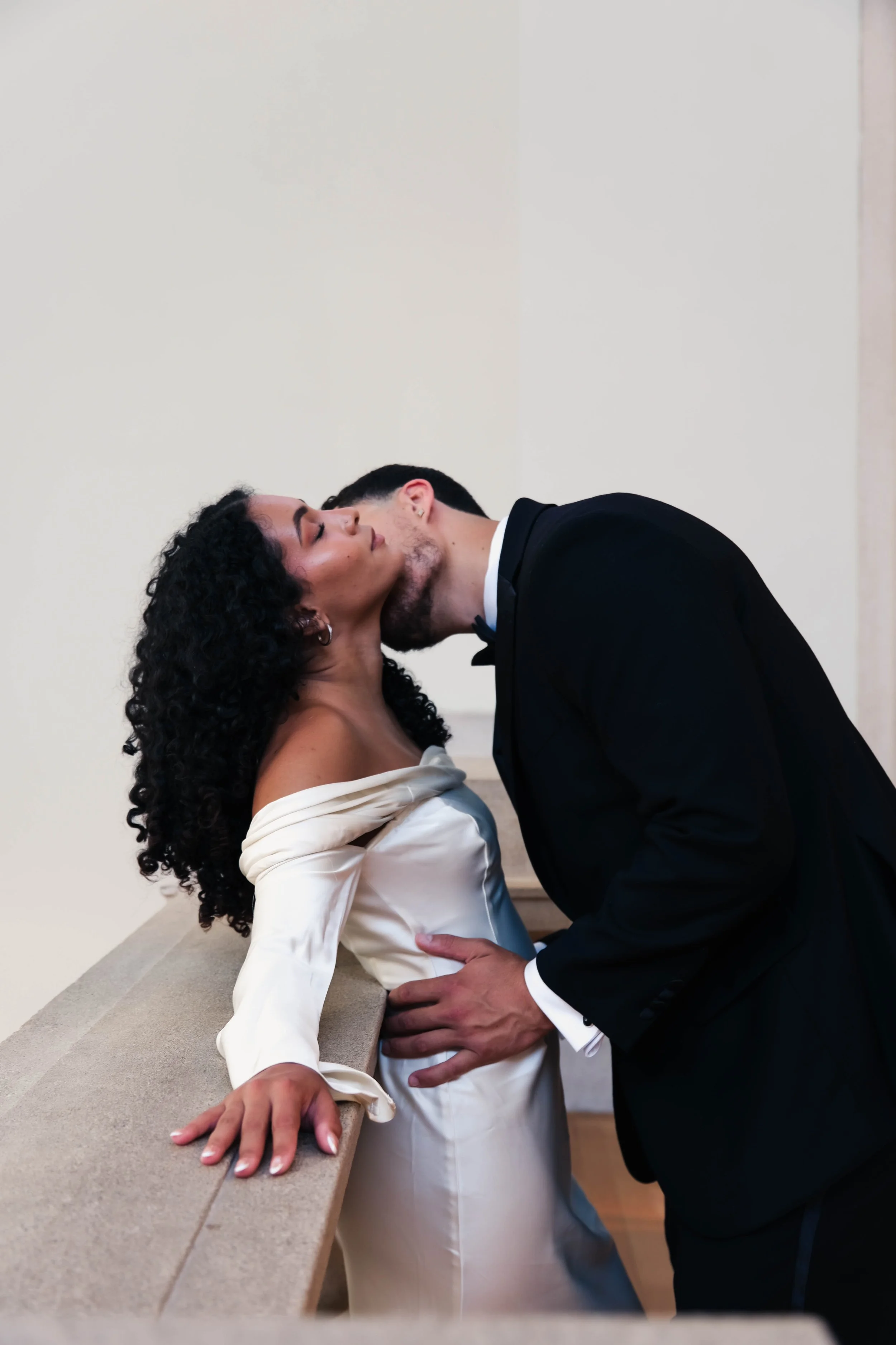 The Met Engagement Shoot  A man in a tuxedo kisses a woman in a white dress.