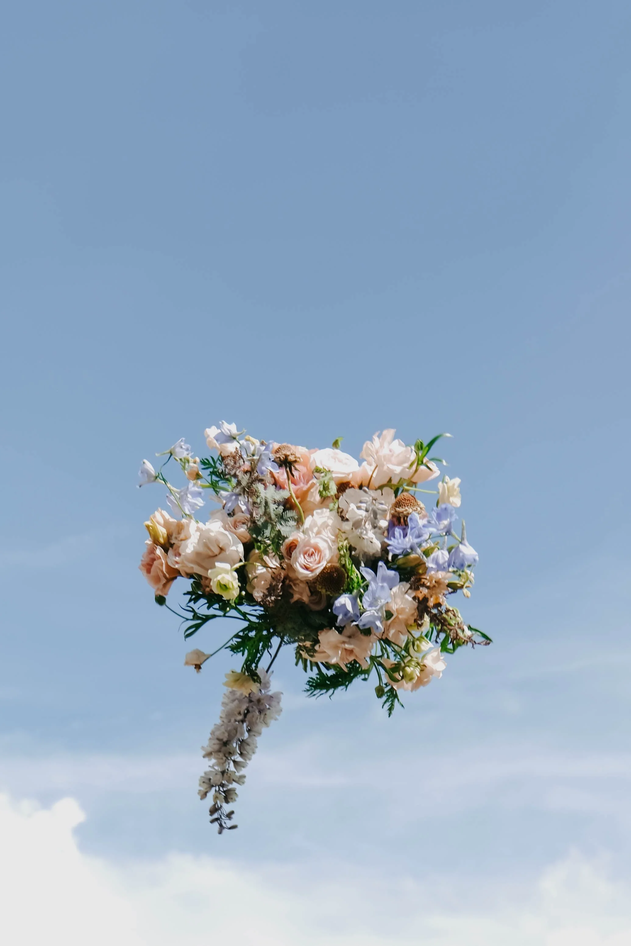 A bouquet of pastel-colored flowers floating against a blue sky.