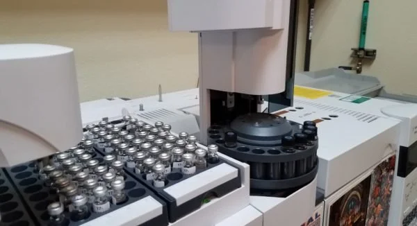 Laboratory equipment with numerous vials, a machine with a circular rotor, and laboratory supplies.