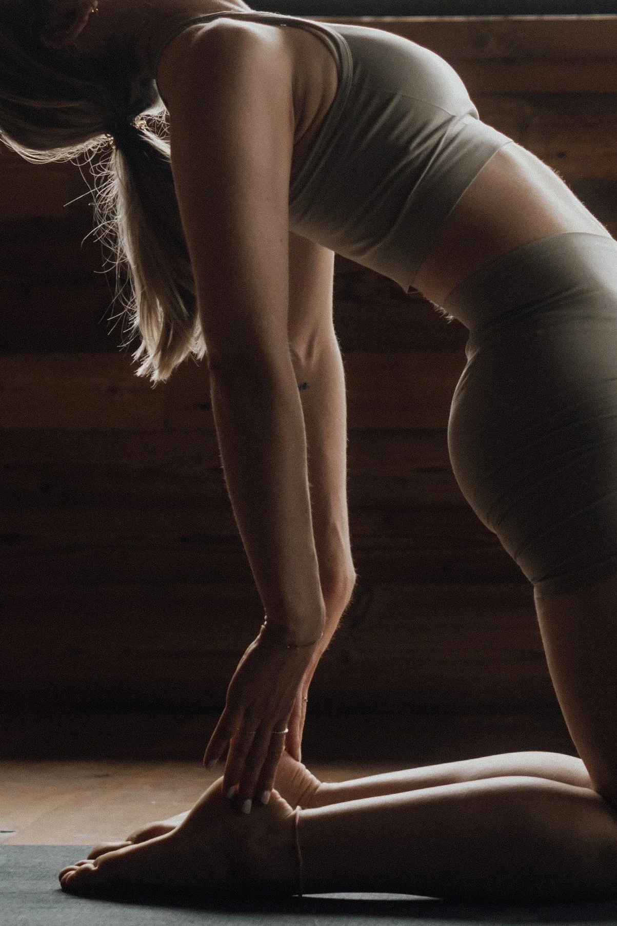 Eine Frau macht Yoga auf einer Matte in einem Raum mit dunklem Holz hintergrund.