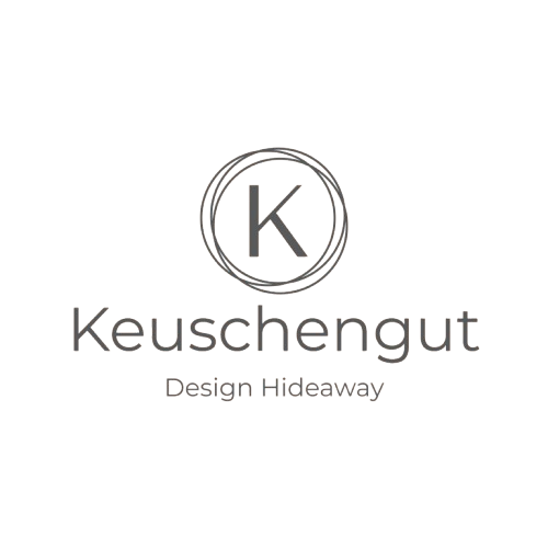 Logo mit dem Buchstaben K in einem Kreis, darunter der Schriftzug 'Keuschengut' und der Slogan 'Design. Hidesaway' auf schwarzem Hintergrund.