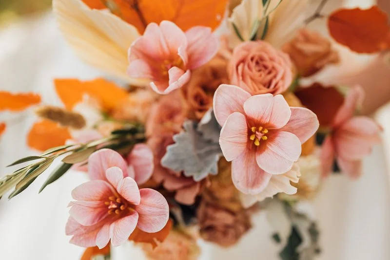 Close-up of a colorful bouquet of pink, orange, and peach flowers with green leaves.