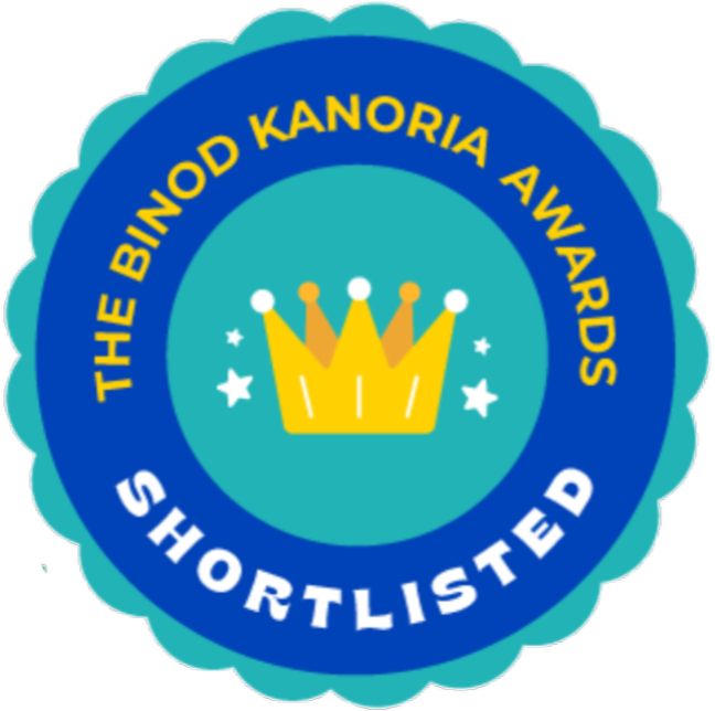 A circular badge with a blue scalloped border. Inside, there is a yellow crown and stars. The text reads 'The BIND Kanoria Awards Shortlisted' in yellow and white letters.