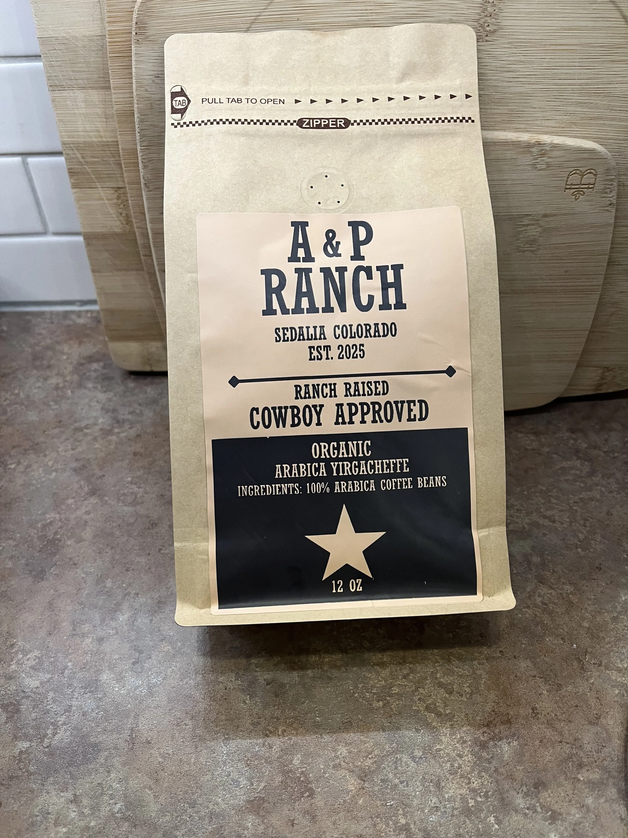 A 12-ounce bag of A&P Ranch organic Arabica Yirgacheffe coffee beans, with a label featuring a star and text indicating it is cowboy approved, ranch raised, and from Sedalia, Colorado.