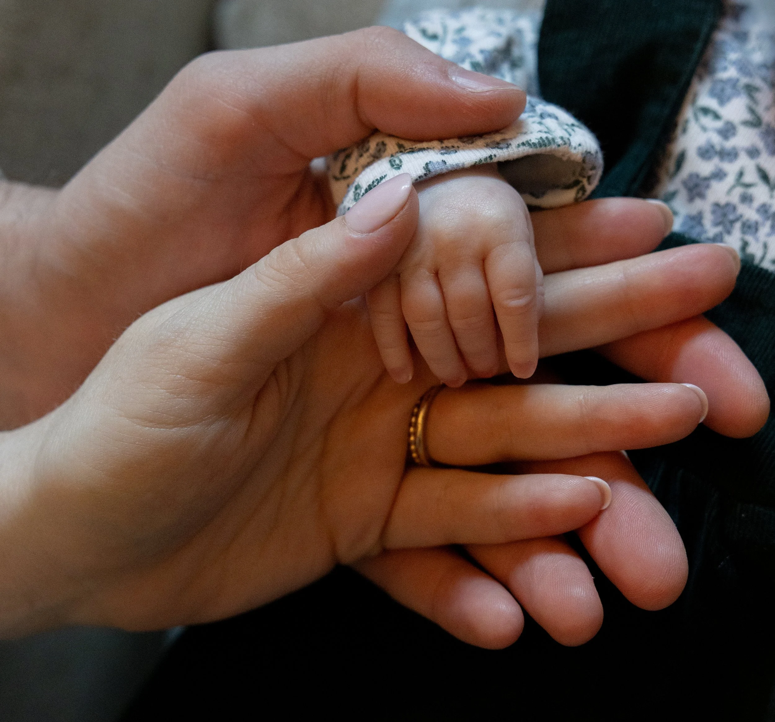 Newborn hand gently grasping parent’s finger, framed in soft light to capture love, protection, and first connection.