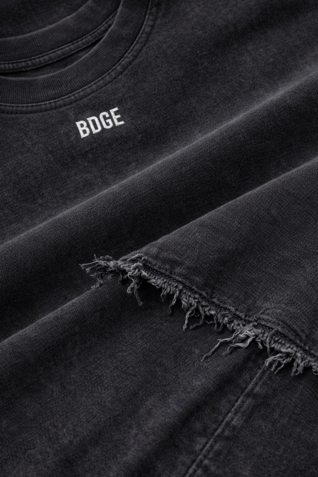 Close-up of a black t-shirt and jeans with the word 'BODE' printed on the shirt and frayed edges on the jeans.