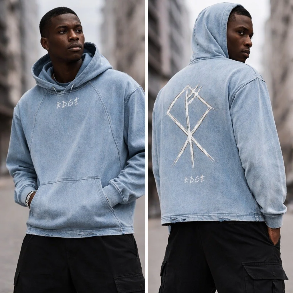 A young man wearing a light blue denim hooded jacket with a large graphic design on the back and some writing on the front, standing outdoors with a city street background.